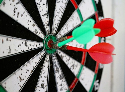 close up of darts in the center of a target, over white background