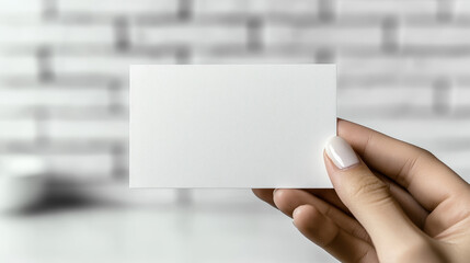 A close-up photograph of an empty white business card, held in a hand against a blurred background with some food items in the background