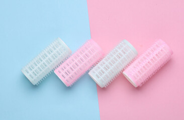 Plastic hair curlers on pink blue background