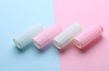 Plastic hair curlers on pink blue background