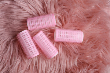 Plastic hair curlers on pink fuzzy background