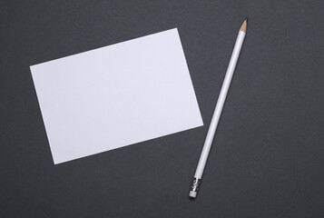 White blank card with pencil on dark grey background