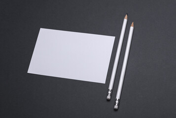 White blank card with pencils on dark grey background