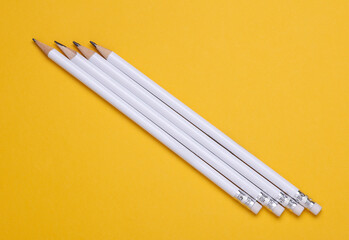 White wooden pencils with erasers on yellow background. Mockup for design
