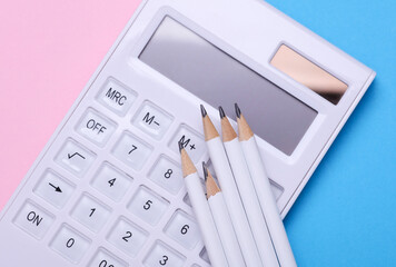 Calculator with pencils on blue pink background