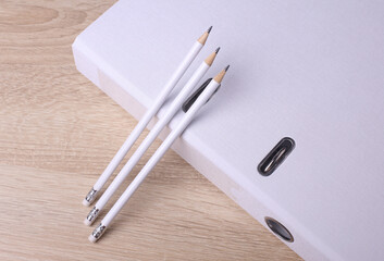White wooden pencils with folder on table. Mockup for design