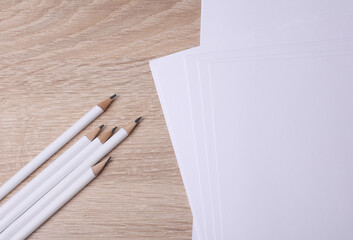 Pencils with white blank sheets of paper on table