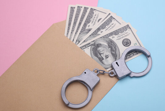 Envelope with money and handcuffs on a pink blue background. Corruption, crime