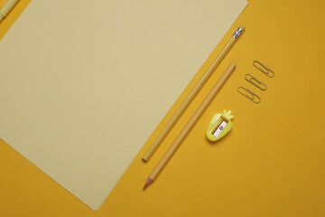 Sheets of paper with school stationery on yellow background. Monochrome photography. Flat lay....