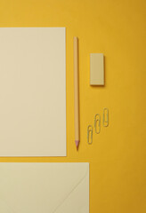Creative layout of stationery, cards and sheets of paper on yellow background. Monochrome photography. Flat lay