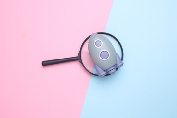 Space shuttle with magnifying glass on blue pink background