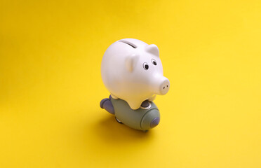 Toy space shuttle with piggy bank on yellow background. Startup idea