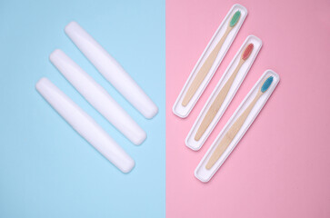 Plastic cases with wooden toothbrushes on blue pink background