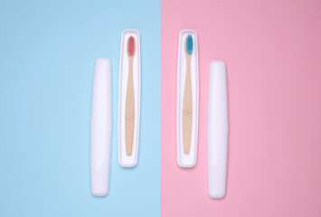 Plastic cases with wooden toothbrushes on blue pink background