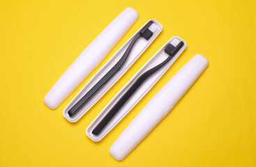 Plastic cases with toothbrushes on yellow background