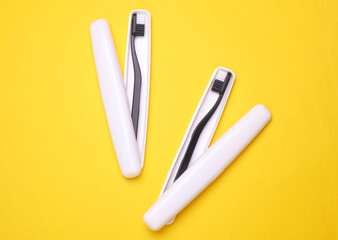 Plastic cases with toothbrushes on yellow background