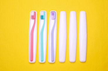 Plastic cases with toothbrushes on yellow background