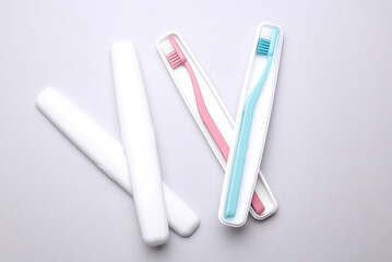 Plastic cases with toothbrushes on gray background