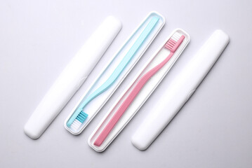 Plastic cases with toothbrushes on gray background