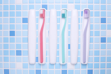 Plastic cases with toothbrushes on tile background