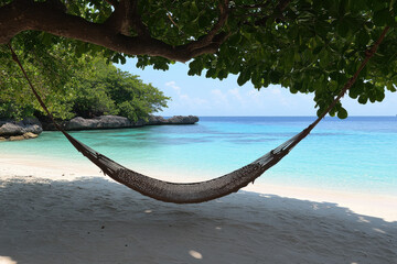 Obraz premium A beach scene with a hammock hanging over the water