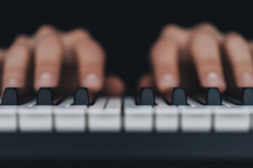 Fototapeta premium Two hands playing a piano with the black keys showing