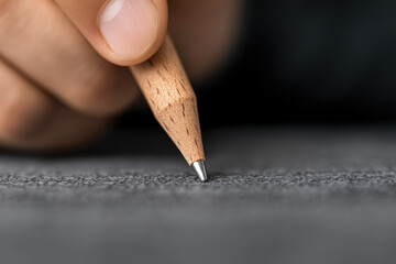 A person is writing with a pencil on a piece of paper