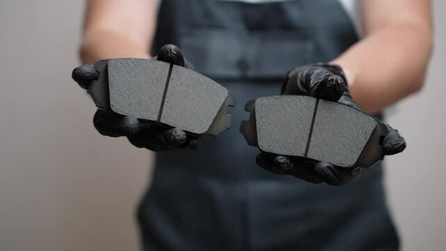 Man holding brake pads in hands, pulling them forward, close-up. Concept of auto parts replacement, car maintenance, good car brake system.