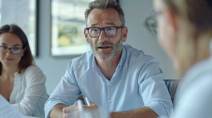 A professional man seated at a conference table, leading a discussion on billing procedures with team members, in a professional office boardroom adorned with contemporary artwork.