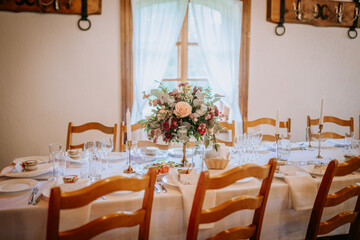A beautifully set table with floral centerpiece, candles, elegant tableware, and wooden chairs in a cozy room with soft natural light.