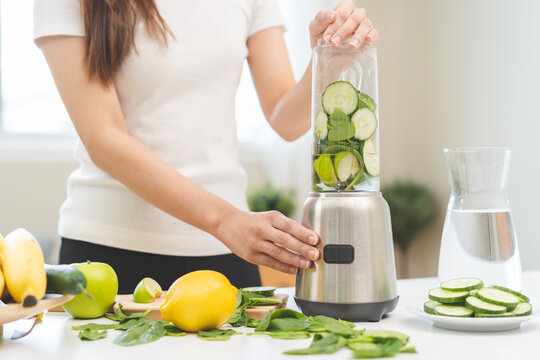 Vegetable smoothie detox, woman hand making healthy raw fresh green fruit juice with blender machine, preparing drink with spinach in kitchen at home, eating vegan diet. Healthy dieting, weight loss.