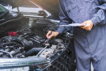 Auto check, car service shop concept. Automobile repairman writing job checklist on clipboard,...
