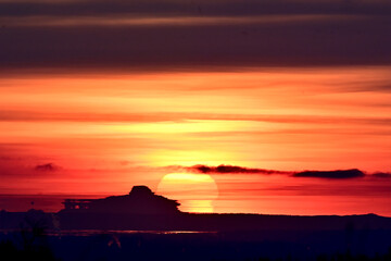 A Fata Morgana mirage, caused by atmospheric refraction bending light waves, distorts the view as the sun sets behind coastal mountains across the Cook Inlet from Anchorage, Alaska.