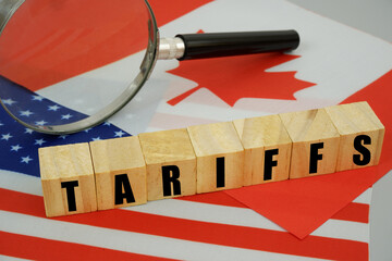 Tariffs between the United States and Canada. USA and Canadian flags, magnifying glass and wooden cubes with word tariffs.