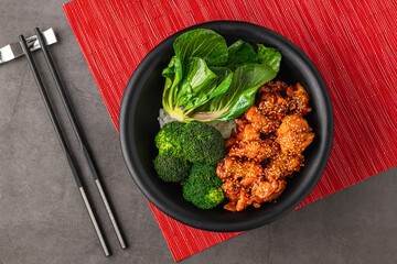 Teriyaki chicken bowl with broccoli and bok choy on gray stone table
