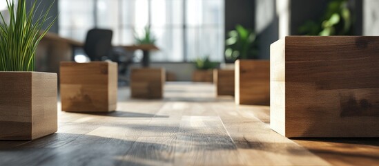 Modern office scene featuring wooden cubes positioned on a wooden floor with natural light from large windows and green plants in the background.