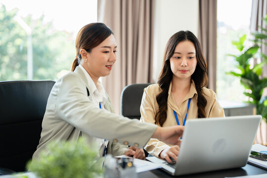 Female senior and junior managers sitting at desk working together in a business team