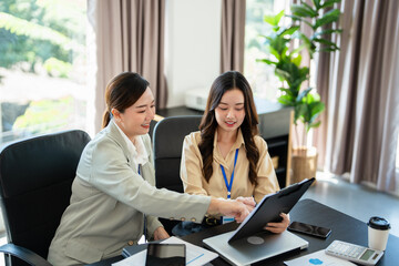 Female senior and junior managers sitting at desk working together in a business team