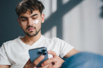 A Young Man Deeply Engaged with His Smartphone While Surrounded by Natural Light