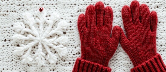Cozy red knit gloves on a white knitted background with a handmade snowflake, emphasizing warmth and winter elegance in the top right corner.