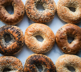 Top view close up of many assorted bagels filling the frame.