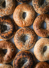 Top view close up of many assorted bagels filling the frame.