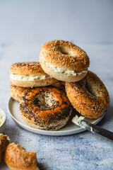 Close up of a pile of assorted bagels with cream cheese.