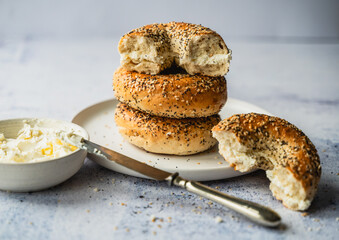Close up of a stack of everything bagels with cream cheese on a plate.