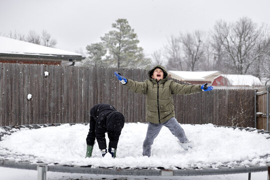 boys playing and laughing on trampoline in the snow