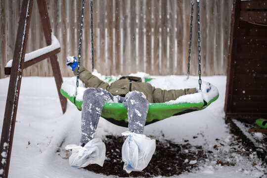 boy in winter clothes laying on a snow-covered saucer