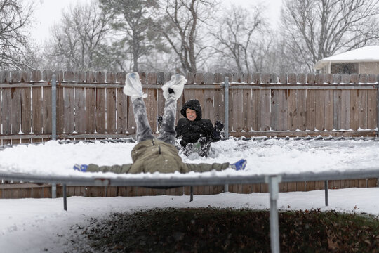 Two kids playing on a snow-covered trampoline in winter