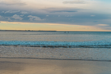 sky and ocean with remote surfers on the horizon