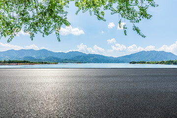 Asphalt road and blue lake with mountain nature landscape under blue sky