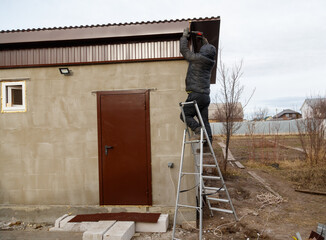 A man is on a ladder, fixing a roof